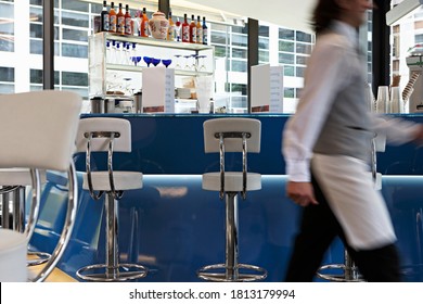 Motion Blur Of A Waiter Walking Across In A Bar.