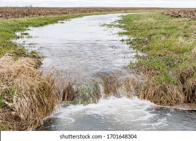 Motion Blur Of Water Flowing In Farm Field Waterway To Ditch After Heavy Rain And Storms Caused Flooding. Concept Of Soil Erosion And Water Runoff Control And Management