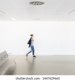 Motion Blur Of Woman Walking At Contemporary White Empty Hallway.