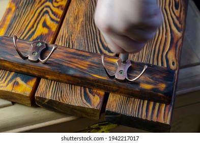 Motion Blur, Wooden Key Holder For The Wall And A Hand With Screwdriver. The Hand Tightens The Screw In Craft Hanger For Keys And Clothes Made Of Brushed Wood. Selective Focus.