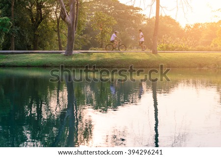 Motion blured of people are running and cycling in urban park with water reflection. 