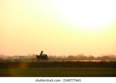 Motion Blurred Image Of Motorcycle Driving Fast On Evening Road