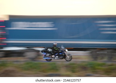 Motion Blurred Image Of Motorcycle Driving Fast On Evening Road