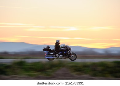 Motion Blurred Image Of Motorcycle Driving Fast On Evening Road