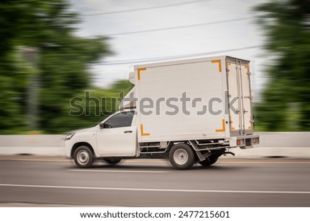 Motion blurred image, of a small white truck for logistics on the roads.