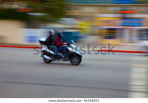Motion Blurred moped\
moving past the camera