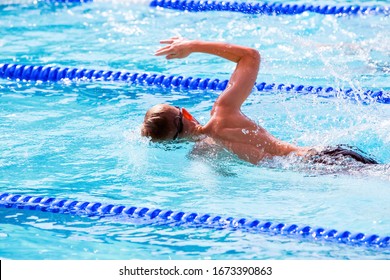 Motion blurred swimmers in a freestyle race, focus on shoulder and water drops
