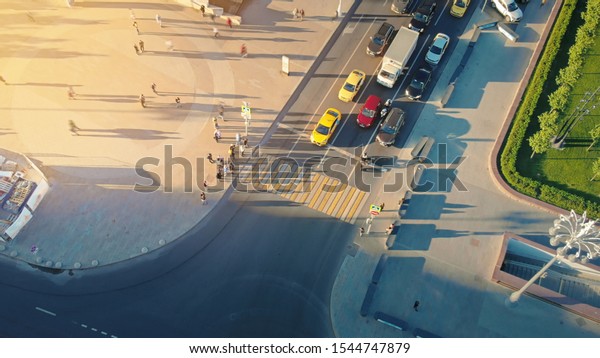 Motion of a busy\
Moscow crossroad on the evening, view from above. Aerial of urban\
scene of hard traffic moving and waiting at traffic lights and\
pedestrians crossing the\
road.