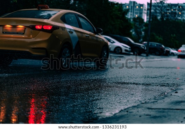 Motion car in rain with selective focus, color\
toned. Night road blurred, in the dark while heavy raining. Back\
light of car on raining road, light reflected on road. View from\
the level of asphalt