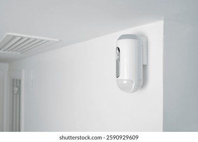 a motion detector equipped with a camera, mounted on a wall, indoors, as part of a burglar alarm system