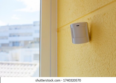 Motion sensor or detector for security system on a yellow wall by the window, indoors. Place for text. - Shutterstock ID 1740320570