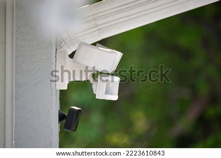 Motion sensor with light detector mounted on exterior wall of private house as part of security system