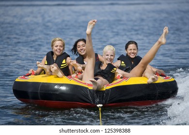 Motion Shot Of Four Women On Inner Tube Wearing Life Jackets