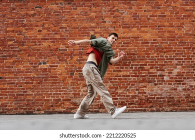 Motion shot of young man dancing hip-hop style outdoors against brick wall, copy space - Powered by Shutterstock