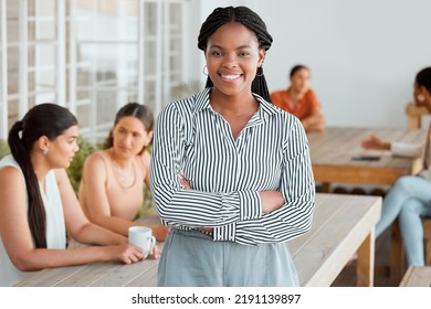 Motivated, Ambitious And Confident Young Business Woman Standing Arms Crossed In The Office Break Room With Colleagues In The Background. Portrait Of A Female Leader Feeling Happy And Positive