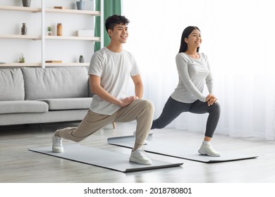 Motivated Asian Young Couple Exercising Together At Home, Positive Korean Man And Woman In Sportswear Standing On Fitness Mat, Stretching And Smiling, Copy Space. Healthy Lifestyle Concept