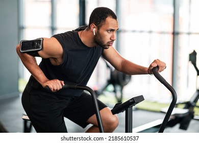 Motivated Black Man Making Cardio Training With Elliptical Bike Machine At Gym, Sporty African American Guy Exercising In Modern Fitness Studio, Enjoying Healthy Lifestyle, Closeup With Free Space - Powered by Shutterstock