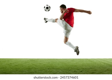 Motivated and competitive male football player hitting ball in jump, during training session of stadium isolated on white background. Concept of professional sport, game, competition, tournament