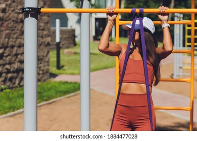 Motivated, concentrated athletic woman doing sports, training , exercising with rubber expander stripe, using elastic rope for muscle stretching and strength workouts. - Powered by Shutterstock