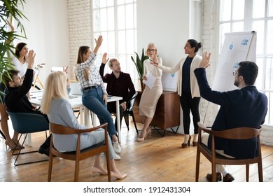 Motivated employees raising hands, asking coach at training. Presenter finishing workshop with questions from engaged audience. Indian female business leader interacting with team at corporate meeting