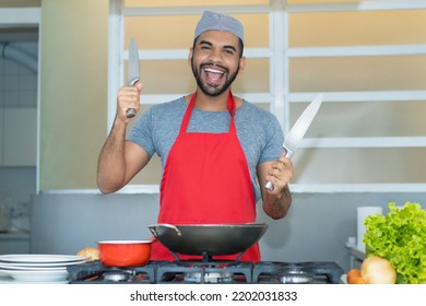 Motivated Hispanic Cook With Red Apron Preparing Food At Kitchen Of Restaurant