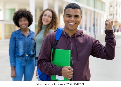 Motivated Latin American Male Student With Backpack And Group Of International Students Outdoor In Summer In City