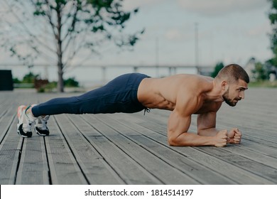 Motivated male athlete does abs exercise, enjoys bodybuilding training outdoor and stands in plank. Strong muscular European adult man has fitness workout. People and healthy lifestyle concept - Powered by Shutterstock