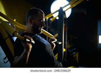 Motivated middle aged man having workout on chest press machine in gym, pushing weight while sitting on bench, building up arms and torso muscles - Powered by Shutterstock