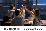 Motivated multinational team raise high fives on briefing after finding problem solution as successful brainstorm result. Happy workers unite hands above conference desk celebrate common achievement