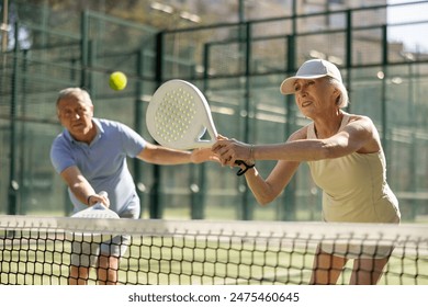 Motivated senior man and woman playing padel with his teammate in court - Powered by Shutterstock