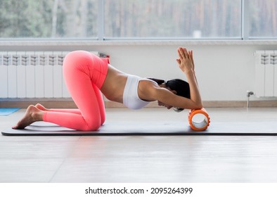 Motivated Sporty Woman Training On Mat Indoor Winter Day, Using Foam Roller Massager For Relaxation, Stretching Spine Muscles, Doing Fascia Exercise. Health Care, Workouts Routine