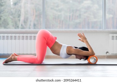 Motivated Sporty Woman Training On Mat Indoor Winter Day, Using Foam Roller Massager For Relaxation, Stretching Spine Muscles, Doing Fascia Exercise. Health Care, Workouts Routine