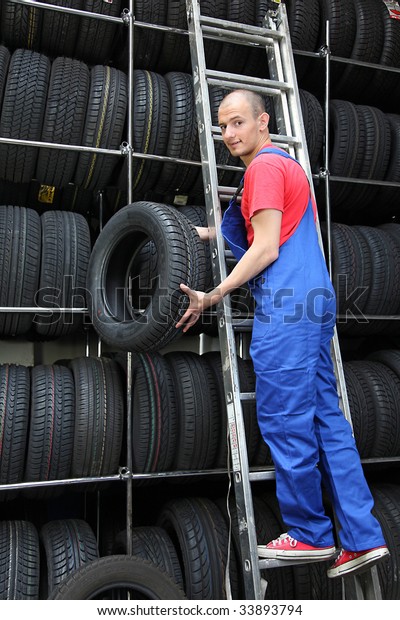 A motivated worker in a tire workshop restocking\
the goods.