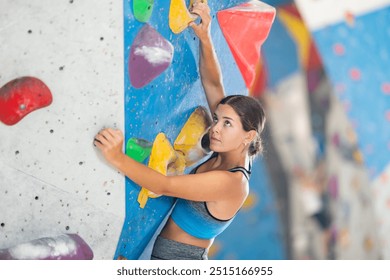 Motivated young girl practicing rock-climbing in large indoor climbing area - Powered by Shutterstock