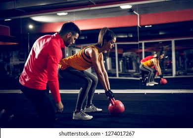 Motivated young sporty female trying to lift weight with a assistance of her coach. - Shutterstock ID 1274017267