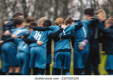 Motivated Youth Soccer Team Cheering On Court. Players Huddling In A Circle On The Field. Coach Talking To A Group Of Soccer Players. Happy Football Team With Their Coach 