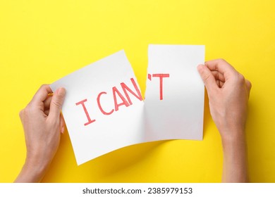 Motivation concept. Woman making phrase I Can from I Can't by tearing paper on yellow background, top view - Powered by Shutterstock