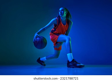 Motivation to win. Young female basketball player in motion during game against blue studio background in neon light. Concept of professional sport, action and motion, game, competition, hobby, ad - Powered by Shutterstock