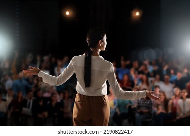 Motivational speaker with headset performing on stage, back view