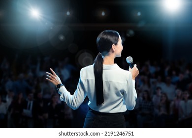 Motivational speaker with microphone performing on stage, back view - Powered by Shutterstock