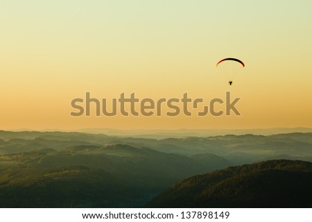 Moto paraglider above the landscape in sunset, copy space