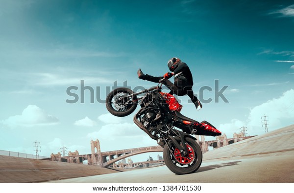 Moto rider making a stunt on his\
motorbike. Biker doing a difficult and dangerous\
stunt.