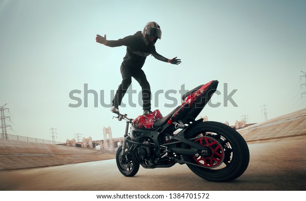 Moto rider making a stunt on his
motorbike. Biker doing a difficult and dangerous
stunt.