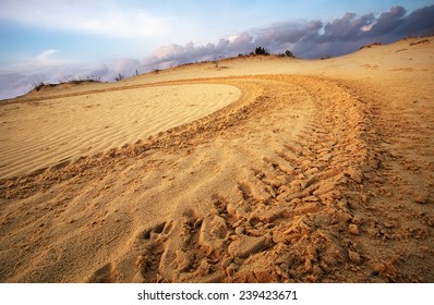 Motocross and auto sport track on blue sky background. Wheel tracks on sand