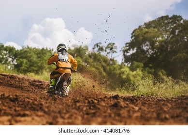 Motocross Racer Accelerating In Dirt Track With Flying Mud Debris