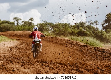 Motocross Rider Accelerating In Dirt Track With Flying Debris Behind