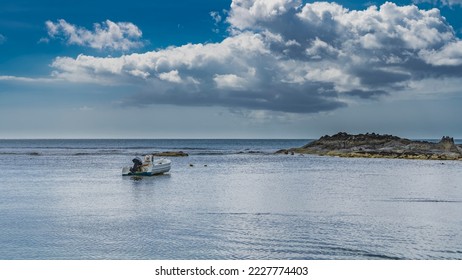 Motor boat in the bay in shallow water at low tide. An island of exposed seabed nearby. Ripples on the water. Picturesque clouds in the blue sky.  Seychelles. Mahe. Beau Vallon - Shutterstock ID 2227774403