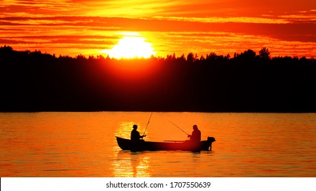 Motor boat with two fishermen (man and woman) on a quiet autumn lake. Sunset and Sunny path on the water. Water voyage, water recreation, float fishing with evening bite. Backlight - Powered by Shutterstock