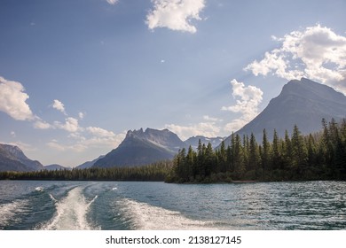 Motor Boat Wake On Waterton Lake With Scenic Mountain Forest Background