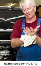 A Motor Mechanic, Cleaning His Greasy Hands After Servicing A Car. Focus On His Hands